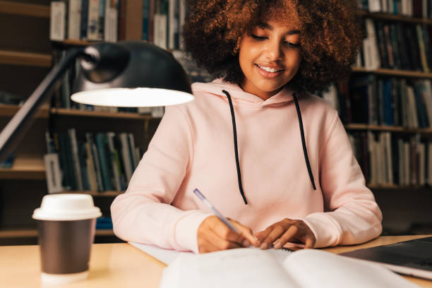 istock Beautiful student with curly hair studying at evening in library 1406408183