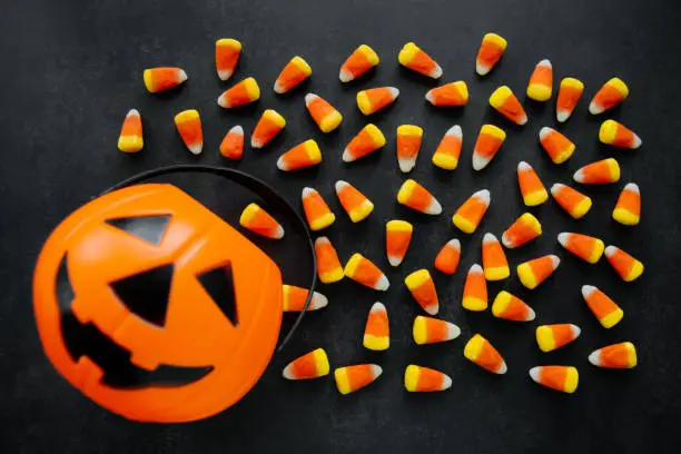 Halloween Background Candy corn candies, pumpkin basket. Traditional sweet Treats. Copy space.