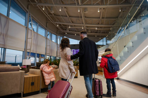 istock Traveling family with suitcases checking flight information on board with timetable, standing in airport departures terminal, waiting to board flight 1406409604