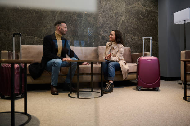 married couple with suitcases, partners on a business trip discussing plans and projects in a vip lounge meeting room while waiting for flight in the airport departure terminal - airport business travel arrival departure board travel imagens e fotografias de stock