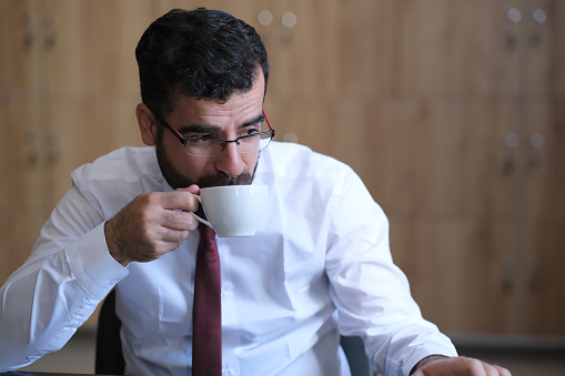 businessman sips coffee in office during business break
