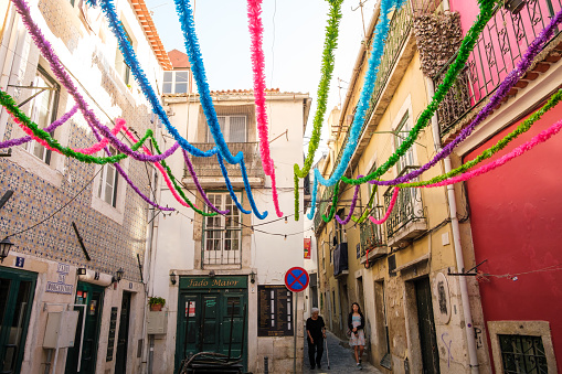 Lisboa , Portugal; 02 July 2022: General view of Largo Peneireiro in Lisbon still decorated for Santo Antonio. Grandmother and granddaughter walk on the street