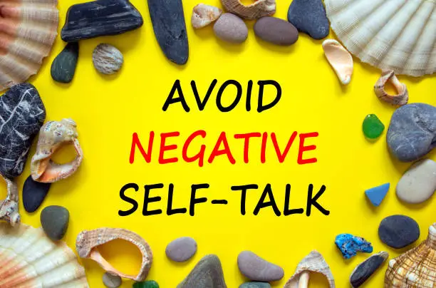Avoid negative self-talk symbol. Concept words Avoid negative self-talk on a beautiful yellow background. Sea stones and seashells. Psychological and Avoid negative self-talk concept. Copy space.