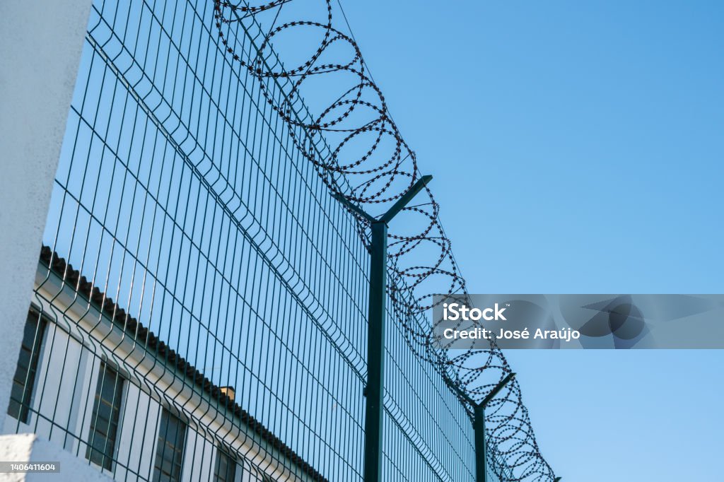 Mesh fence with barbed wire on top Fence Stock Photo