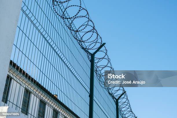 Mesh Fence With Barbed Wire On Top Stock Photo - Download Image Now - Fence, Emigration and Immigration, Prison