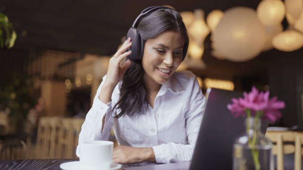 istock Nomad on work. Confident young Latin woman making video call on laptop while sitting by window in cafe. 1406413856