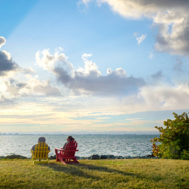 istock Two happy women sitting by seaside and watching view 1406414430