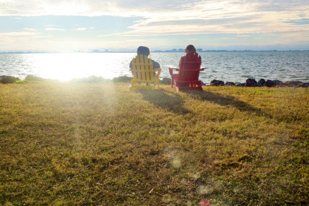 istock Two happy women sitting by seaside and watching view 1406414431