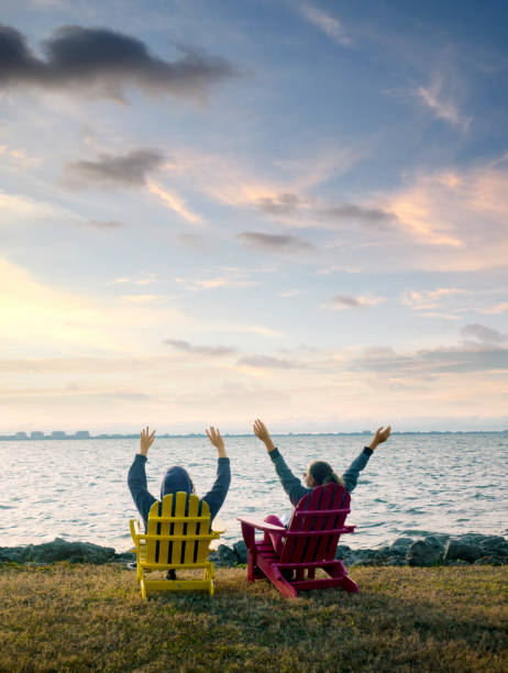 istock Two happy women sitting by seaside and watching view 1406414457