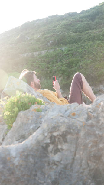 istock Man looking his phone in a beach rock 1406420498