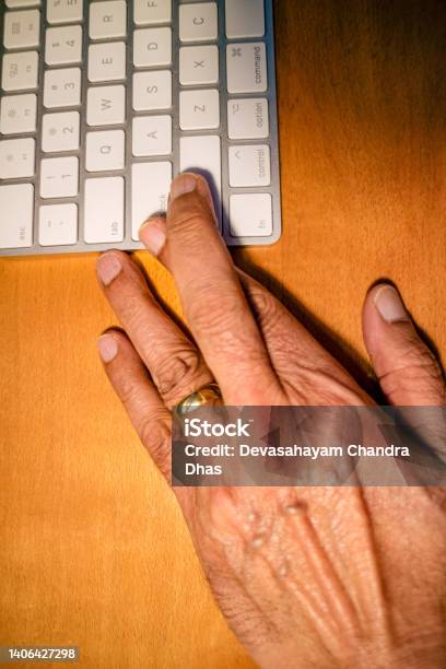 Senior Asian Hand With Fingers Crossed After Having Hit Enter On A Computer Keyboard And Taken A Chance Stock Photo - Download Image Now