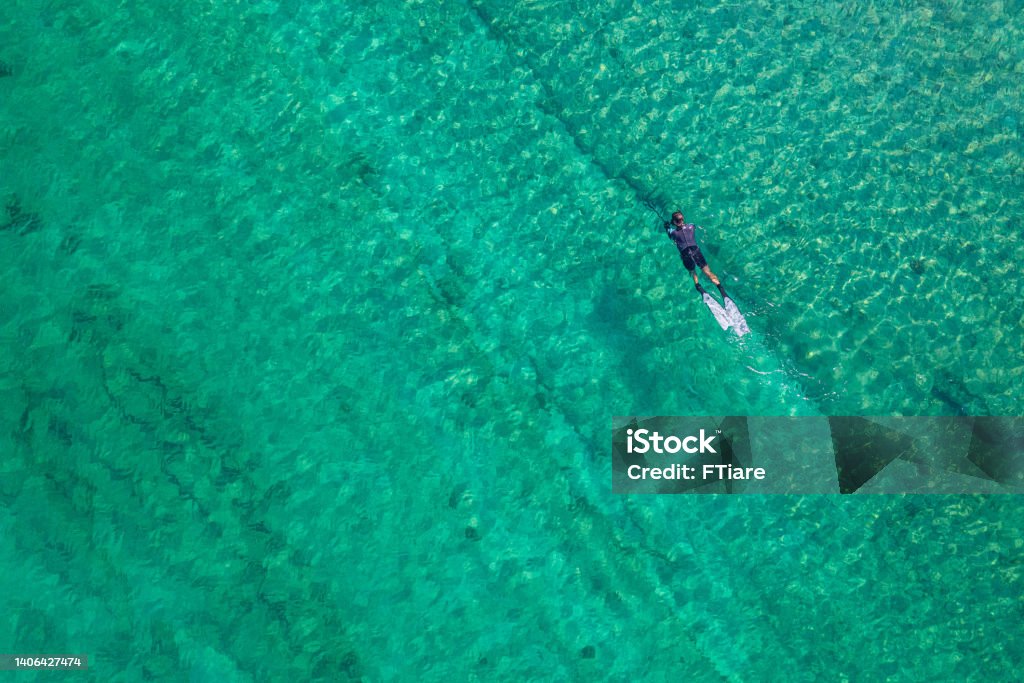 Spearfishing scuba diver in tropical exotic sea, ocean turquoise clear water. Man swimming hunting exotic fish, poaching. Top view. Aerial, drone, copter view. Adult Stock Photo