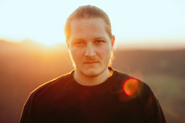 istock Young Man Looking Towards The Camera Outdoors at Sunset Millennial Generation Summer Portrait 1406434845