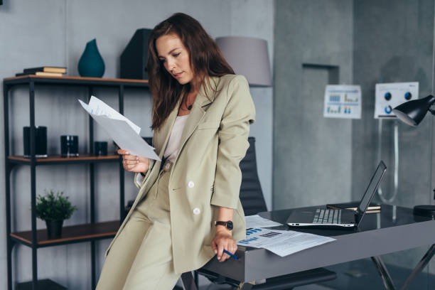 istock Woman stands at desk and looks through documents. 1406436492