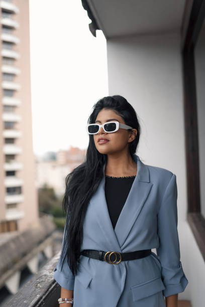 touchant ses cheveux longs porter blazer gris, ceinture et lunettes de soleil jeune femme latine - glamour urban scene beautiful one person photos et images de collection