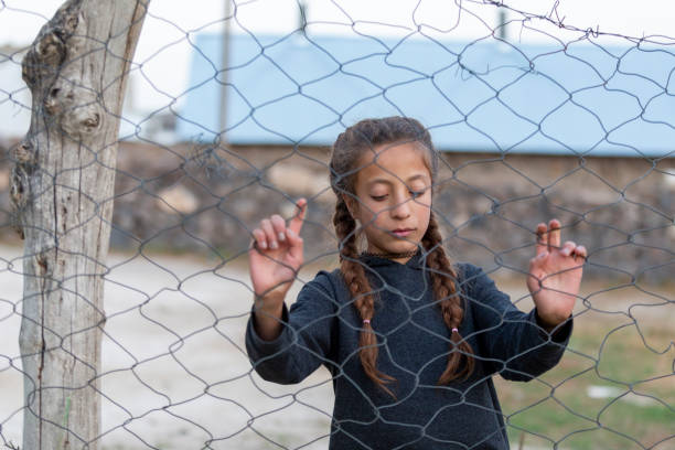 Refugee girl behind fence.