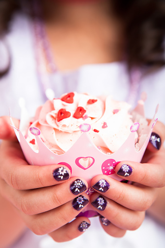 8 years old girl celebrating birthday holding cupcake up close.