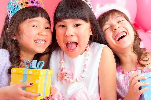Laughing three girls best friends celebrating birthday on pink background