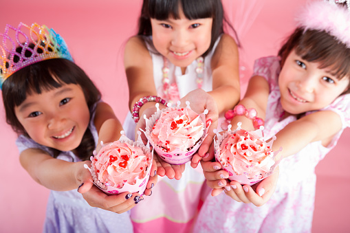 a little happy child girl in a red dress with a rose in her hand on a white isolated background laughs and smiles, the concept of Valentine's day, a place for text