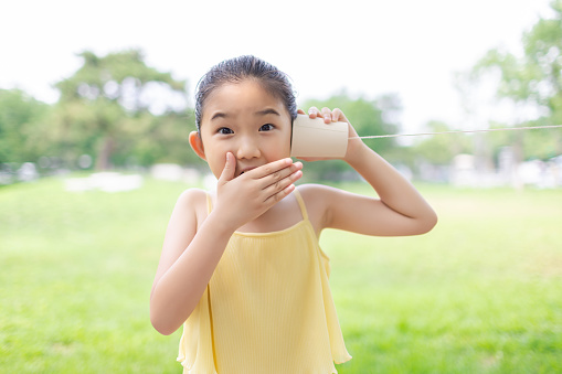 Little Girl is Playing Tin Can Telephone