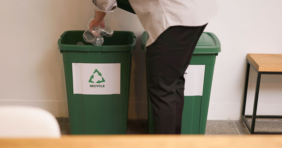 Waste separation and environmental friendly - Man throwing plastic bottle into recycling bin in office