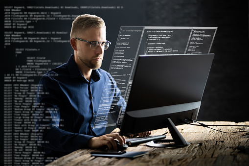 Computer Programmer Writing Program Code On Computer In Office