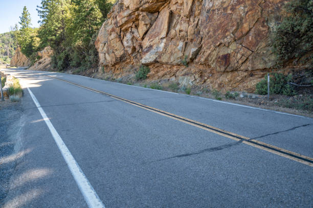 stony rock mountain wall next to a mountain road in which metal fasteners have been drilled for rock safety.