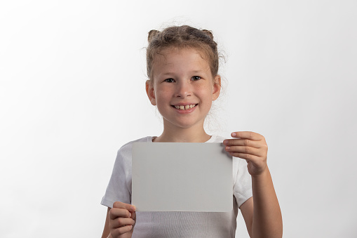 Little girl holding a plain white sign isolated on a white background smiling at the camera
