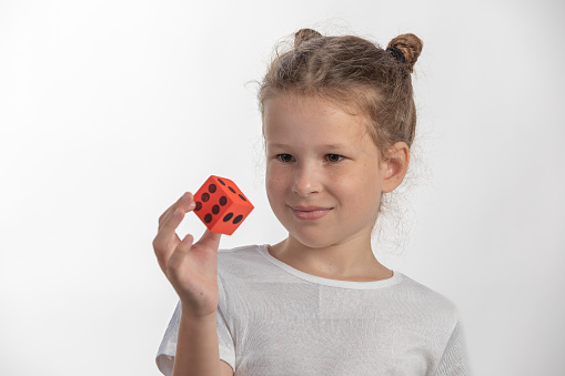 Pretty young girl holding a large, red dice - on white background