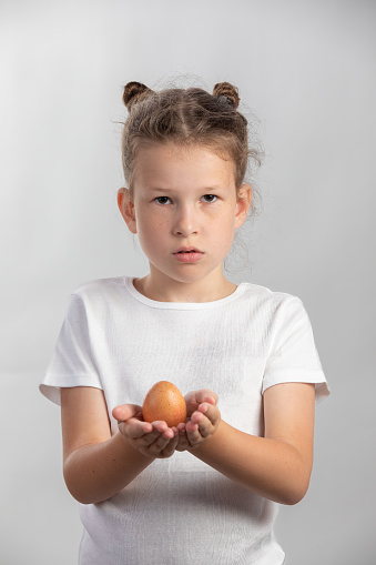Little girl holding one egg - on white background