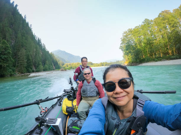 60+ Senior Multiracial Friends Riding Boat While Freshwater River Fishing stock photo