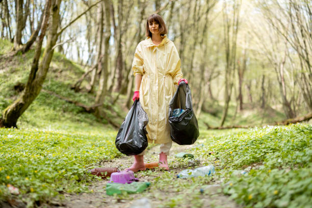istock Woman collecting scattered plastic garbage in the woods 1406476548