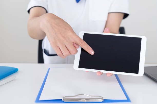 A nurse woman is operating a tablet and explaining at the hospital stock photo