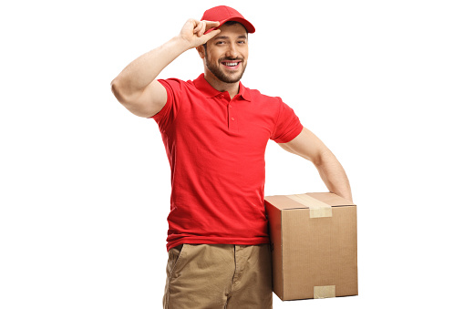 Delivery man with a box smiling and greeting with cap isolated on white background