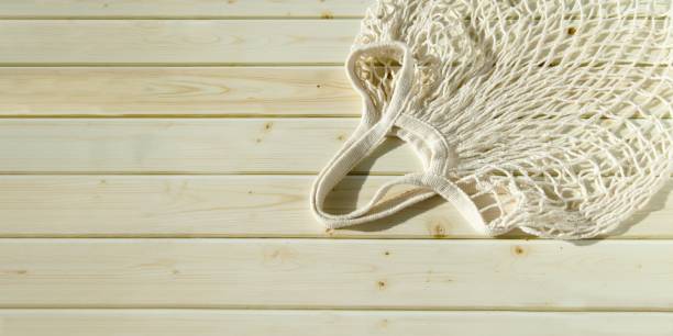 istock Empty wicker mesh bag on background of wooden tabletop made of sanded planks. White empty string bag 1406482850