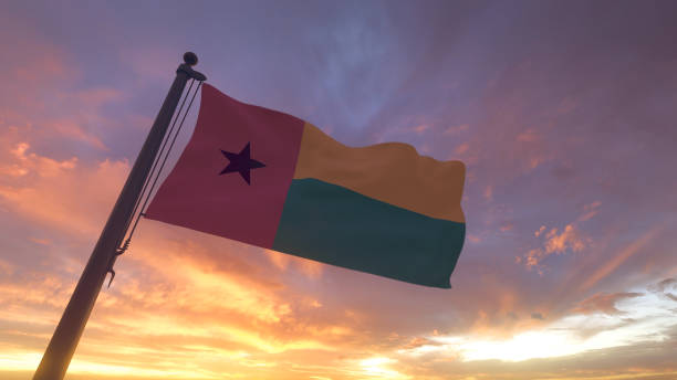 Guinea-Bissau Flag on Flagpole by Evening Sunset Sky stock photo