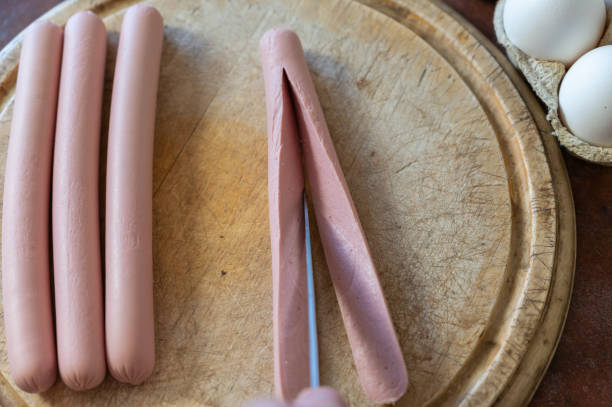 un hombre está cortando una salchicha con un cuchillo. un macho adulto corta una salchicha en una tabla de cortar. cocinar una comida. truco de selección. - 5549 fotografías e imágenes de stock