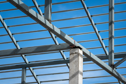 Steel beam roof structure of the house building, on blue sky background. Construction industrial working site and object photo..