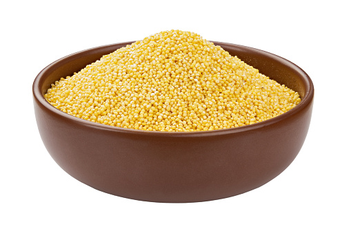 Dry millet groats in ceramic bowl, isolated on white background. Full depth of field. File contains clipping path.