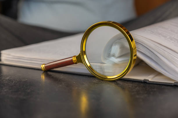 A magnifying glass next to an open file folder. Gray file folder with binder. Close-up. Selective focus.
