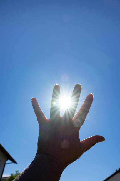 istock Rays of sun between a hand and a blue sky 1406486743