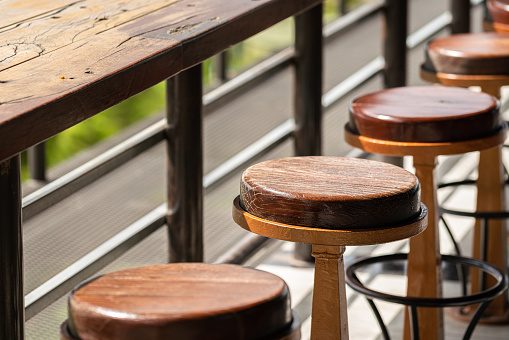 Row of vintage style wooden table bar and round seat without people. Interior decoration and object photo. Selective focus.