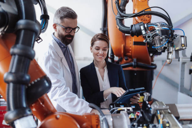 istock Robotics engineers with tablet dicussing and desinging modern robotic arm in factory. 1406492746