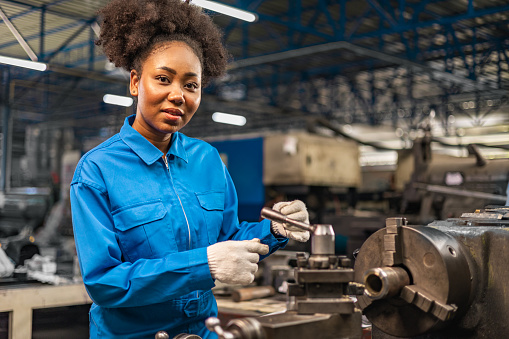 African American Young woman worker  in protective uniform operating machine at factory Industrial.People working in industry.Portrait of Female  Engineer at work place.