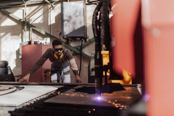 istock Man working on laser cutter of metal, modern technology in process at metalworking manufacturing plant. 1406492901