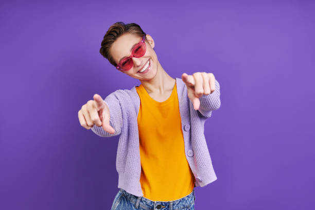 istock Cheerful young woman pointing camera 1406495079