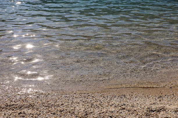 istock Small pebble stones on sea beach with transparent water 1406495465