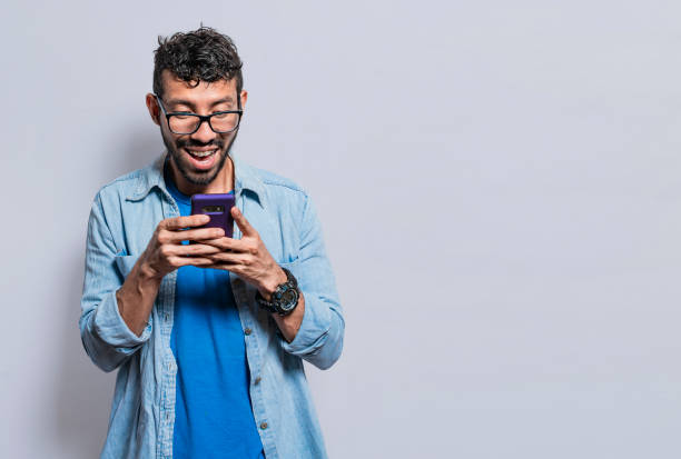 istock Smiling handsome boy texting with his cell phone isolated, young latin man happy with his cell phone isolated, happy teenager texting with his cell phone 1406496696