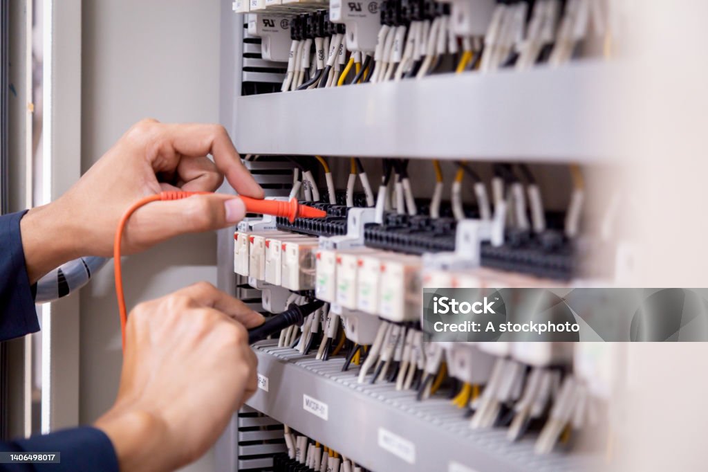 Electrical engineer using measuring equipment to checking electric current voltage at circuit breaker and cable wiring system , Electrical service concept . Electric Switchboard Stock Photo