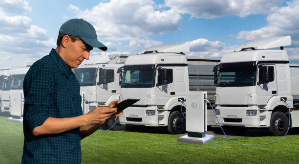 istock Fleet manager with a digital tablet stands next to electric trucks 1406501363